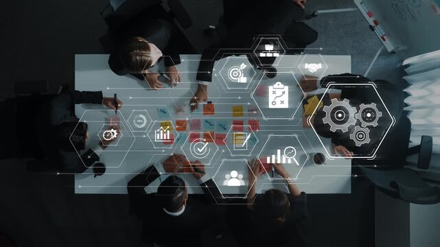 Overhead view of a business team engaged in a strategy session, highlighting technology icons that symbolize innovation and collaboration in a modern workspace. Raster