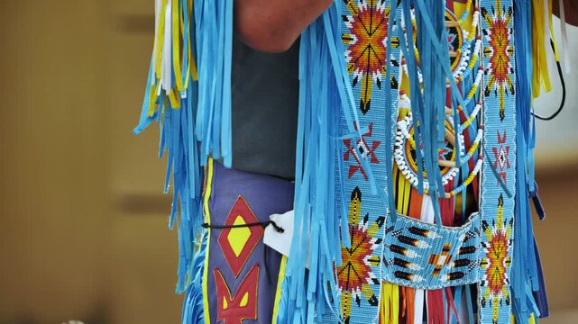 Native American regalia showing vibrant beadwork and blue fringe at a cultural event