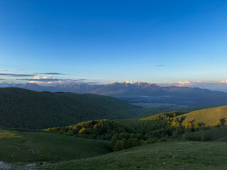 Fototapeta premium Panorama montano con valli verdi sotto cielo azzurro cristallino.