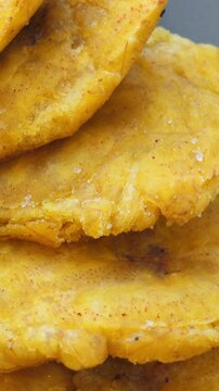 Fried platanos on plate. Sliced and cooked tostones. Rotating. Vertical footage