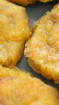Fried platanos on plate. Sliced and cooked tostones. Rotating. Vertical footage