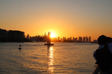 Fototapeta premium Silhouette of the mainland Miami skyline with cranes and construction sites along the canal at South Pointe Park during sunset, showing urban development and waterfront scenery. 