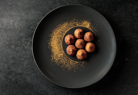 Chocolate truffles on a black plate.