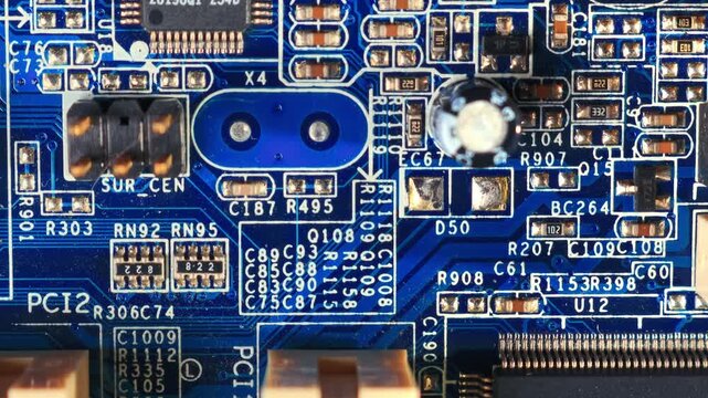 Extreme close-up macro shot of blue PCB showing PCI slots, SMD components, tactile switch and dense silkscreen markings under studio lighting