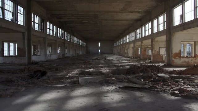 Panning shot across abandoned factory interior revealing debris and sunlight through high row of windows
