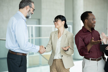Diverse business people making a deal and greeting each other, reflecting collaboration and a successful corporate meeting © Dejan