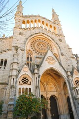 Obraz premium Cathedral Sant Bartomeu in Sóller, Tramuntana Region, Mallorca West Coast, Balearic islands, Mediterranean Sea, Spain, featuring an orange tree next to the church entrance.