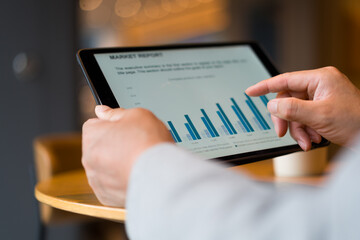 Person holding a tablet viewing market report with bar chart data analysis