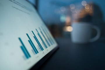 Tablet computer displaying data charts alongside a coffee cup on a desk