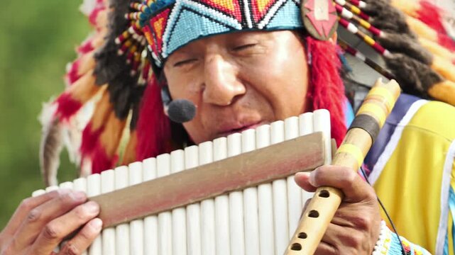 Traditional musician playing panpipes and a flute, performing folk music outdoors