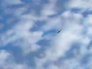 Small yellow airplane flying against a backdrop of clouds, symbolizing freedom and adventure