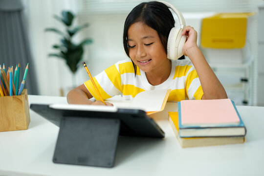 Asian girl with headphones enjoying online class on digital tablet