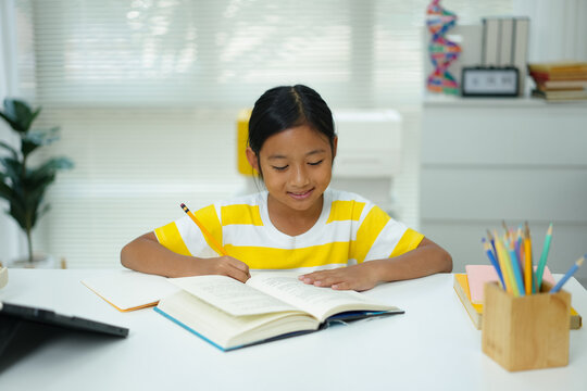 Asian girl reading book and writing in notebook for study at home