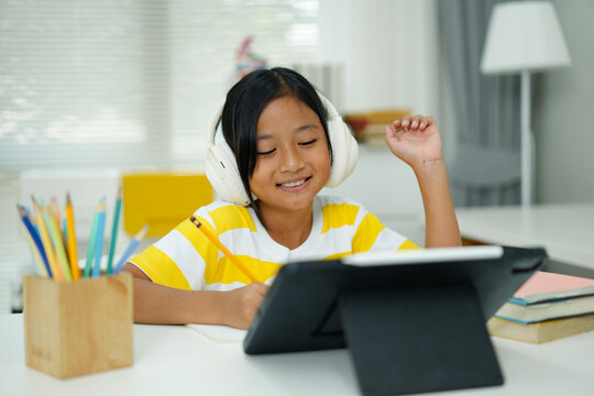 Asian girl with headphones enjoying online class on digital tablet