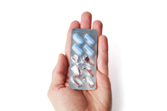 Hand holding silver blister pack of blue naproxen capsules for pain relief on white background