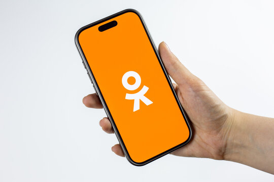 Moscow, Russia, March 14, 2026: Hand holding smartphone displaying the OK orange logo on screen, isolated. Visual representing nostalgia, returning to platform after years and reconnecting with past
