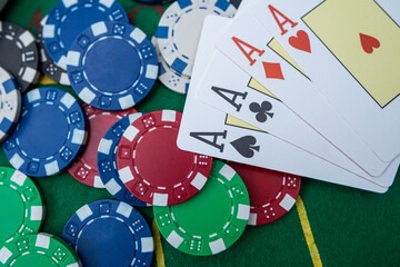 Four aces poker hand with casino chips on green gambling table