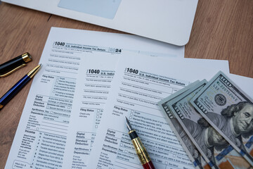 1040 Business tax paperwork with laptop pen and cash money on modern wooden office desk