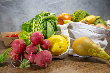 Reusable fabric bag filled with fresh organic vegetables on kitchen table.