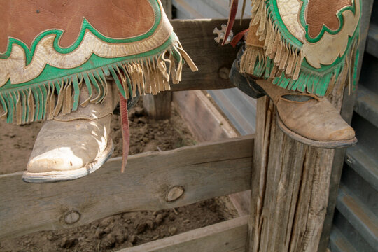 Western boots and fringed leather chaps at a rodeo