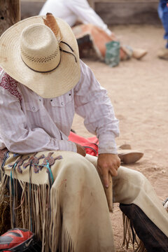 Cowboy brushing the leather of his chaps at a rodeo