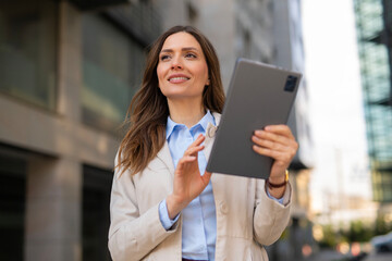 Fototapeta premium Businesswoman using digital tablet walking in city
