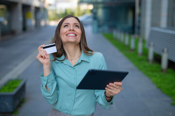 Fototapeta premium Woman smiling holding credit card and tablet shopping online