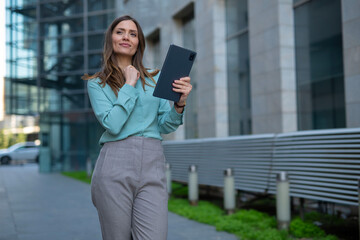 Fototapeta premium Businesswoman standing outdoors using tablet technology device