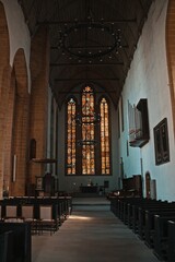 Fototapeta premium Interior of a historic Gothic church with stained glass windows in Erfurt, Germany. Medieval architecture, wooden ceiling and altar illuminated by colorful glass.