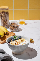 Natural greek yogurt with granola, blueberry and banana in a bowl on a marble table © Kufotos