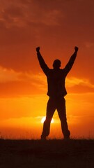 Fototapeta premium Silhouette of triumphant man with arms raised at sunset
