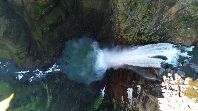 Aerial drone view of water cascading over the edge of Maletsunyane Falls into the river far below, showing the powerful waterfall and surrounding canyon landscape