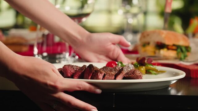 Beef angus steak in restaurant, close up Pieces of hot ribeye steak served on the wooden board. Medium steak slices with blood, salt and pepper in fancy meat cafe. 