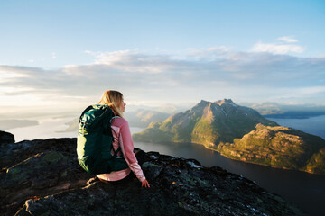 Naklejka premium Woman travel solo in Norway backpacker girl hiking mountains on summer holiday retreat, tourist enjoying aerial sea view from summit active adventure vacations healthy lifestyle harmony with nature