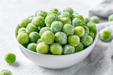 Bowl of frosty bright green Brussels sprouts on textured white surface with cloth