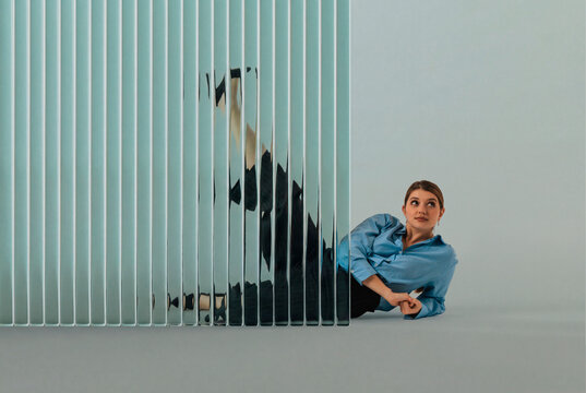 woman reclining beside translucent ribbed glass 3D wall with distorted reflection