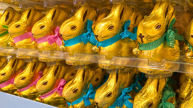 Heidelberg, Germany - March 14 2026: Group of traditional chocolate Easter bunnies in gold foil, colorful ribbon, and bell of a Lindt Gold Bunny on display in a trendy gift shop for the spring holiday
