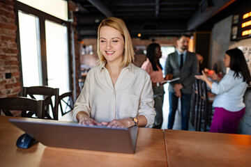 Smiling woman working on laptop in modern cafe