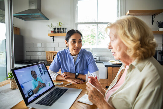Caregiver and senior patient on telehealth video call in home kitchen