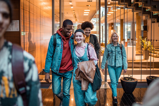 Group of college friends walking through a modern campus building