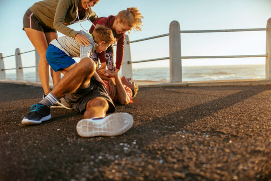 Parents and kids playing on seaside promenade at sunset