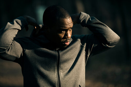 Athletic man adjusting hoodie outdoors at sunrise