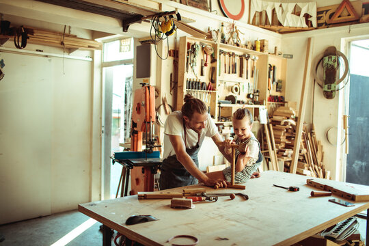 Parent and child woodworking together in home workshop