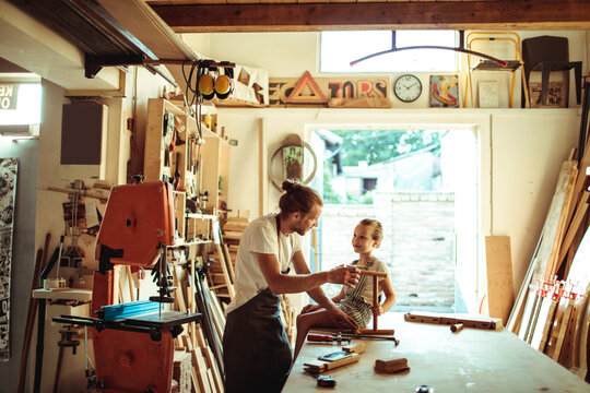 Parent teaching child woodworking in home workshop