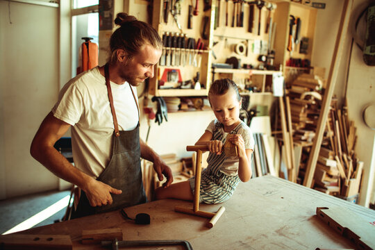 Father and daughter woodworking in home workshop