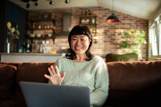Smiling woman waving during video call at home