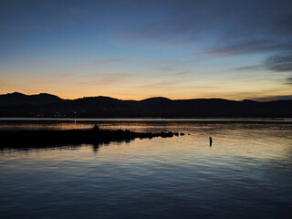 Dusk settling over mountains reflecting on calm lake water © larrui