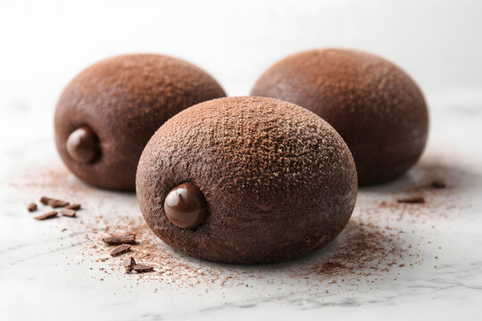 A single chocolate bomboloni dusted with cocoa powder displayed in minimalist composition