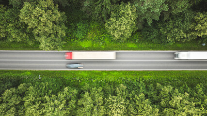 Aerial view of trucks driving on a highway through a lush green forest © Pavel Babic
