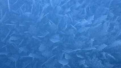 Obraz premium Close-up abstract background of jagged blue frost crystals highlighting the sharp textures of deeply frozen ice.